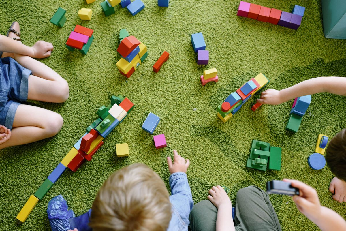 Children playing with colourful wooden blocks on a green carpet
