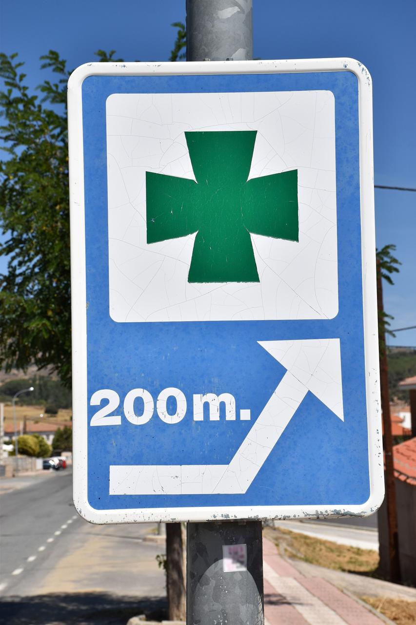 Pharmacy sign with a green cross on a street in Spain